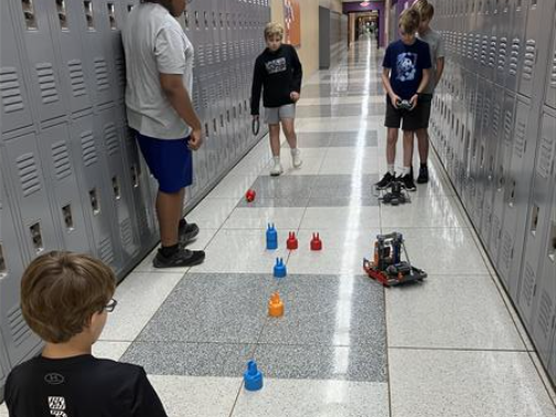 Students driving a robot toward scoring elements.